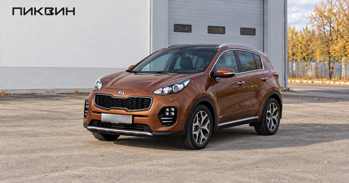 Бронзовый Kia Sportage четвёртого поколения стоит перед закрытым сервисным боксом.