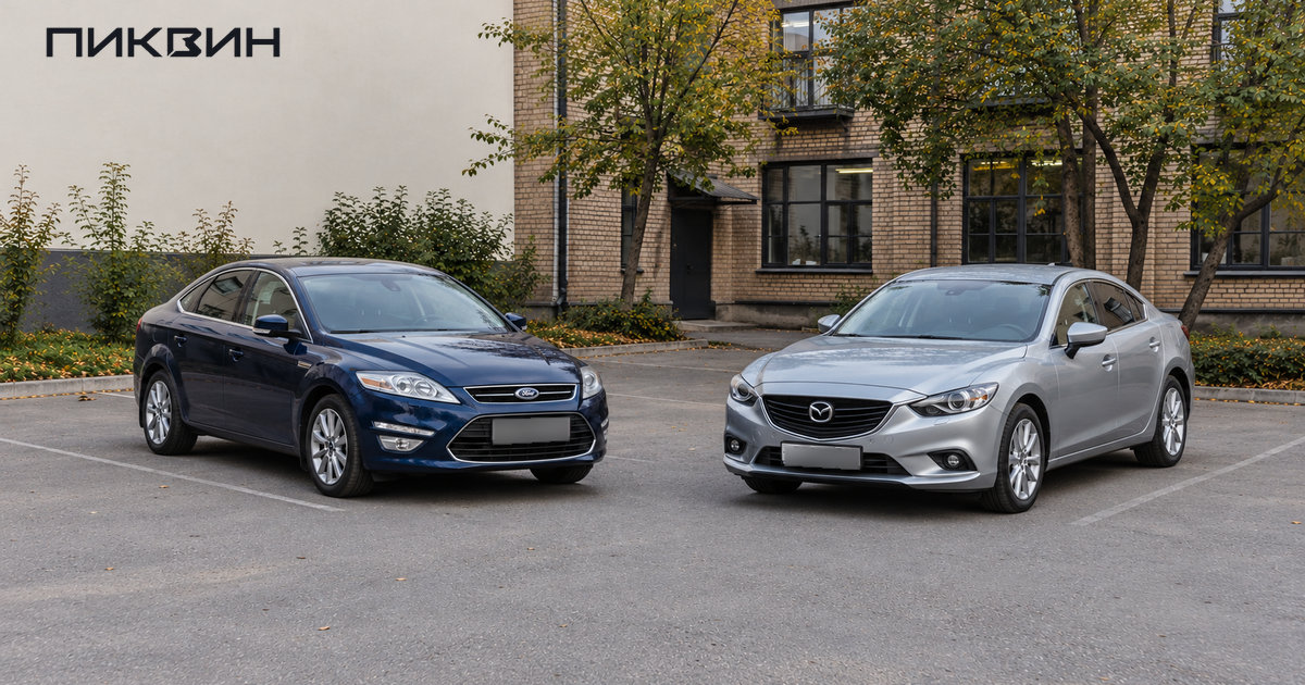 Тёмно-синий Ford Mondeo и серебристая Mazda 6 стоят в соседних местах на площадке подержанных автомобилей.