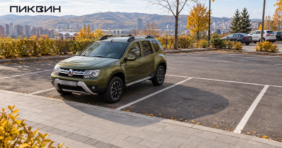 Renault Duster стоит внутри размеченного места у свободного тротуара на осенней городской парковке.