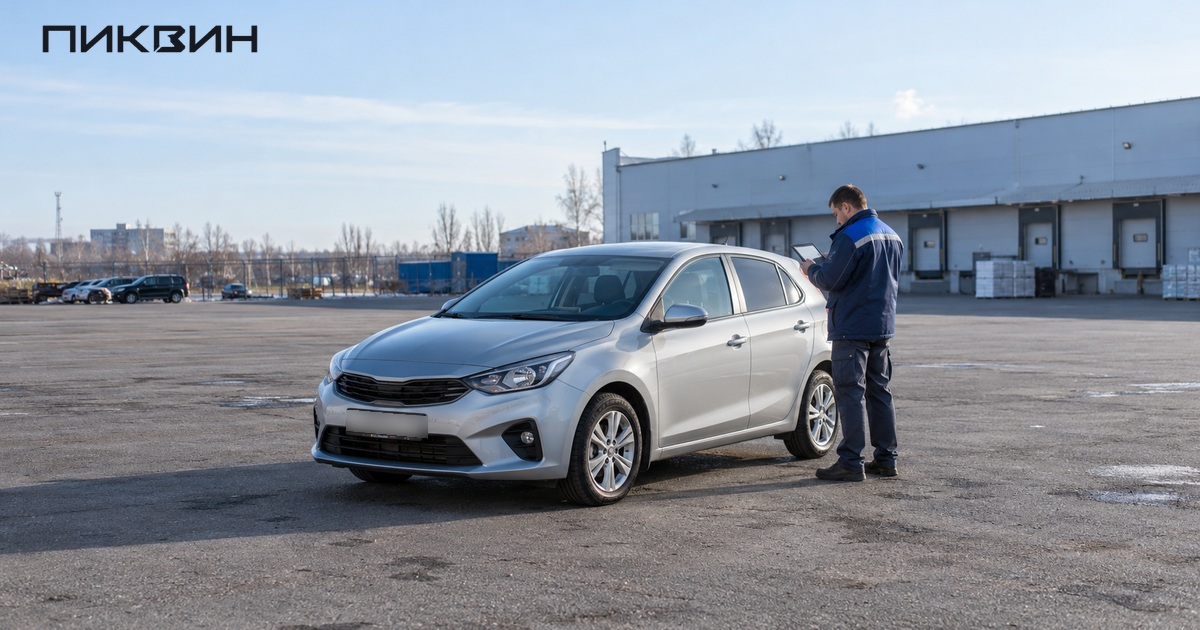 Сотрудник проверяет состояние автомобиля по фотографиям на планшете после перевозки.