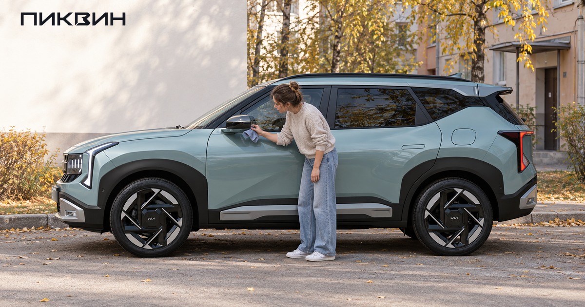Владелец протирает камеру под левым зеркалом Kia Seltos перед проверкой обзора.