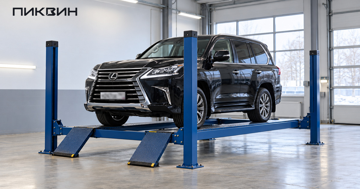 Тёмный Lexus LX 570 стоит на колёсных платформах четырёхстоечного подъёмника в светлом боксе.