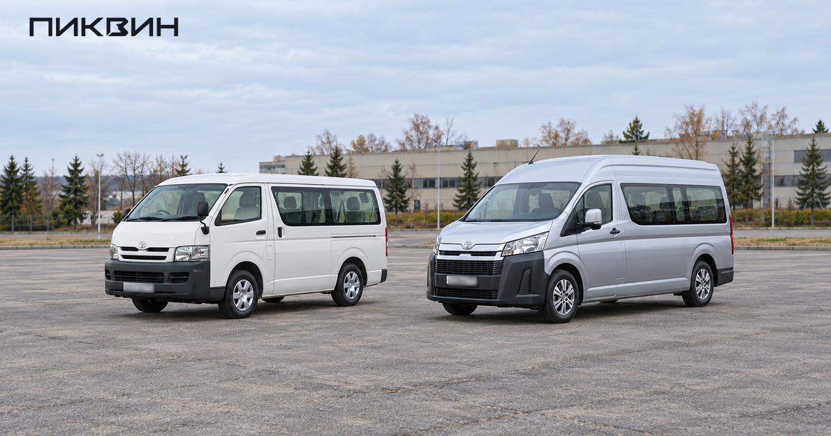 Белый Toyota Hiace H200 и серебристый высокий Hiace H300 стоят раздельно на автобусной площадке.