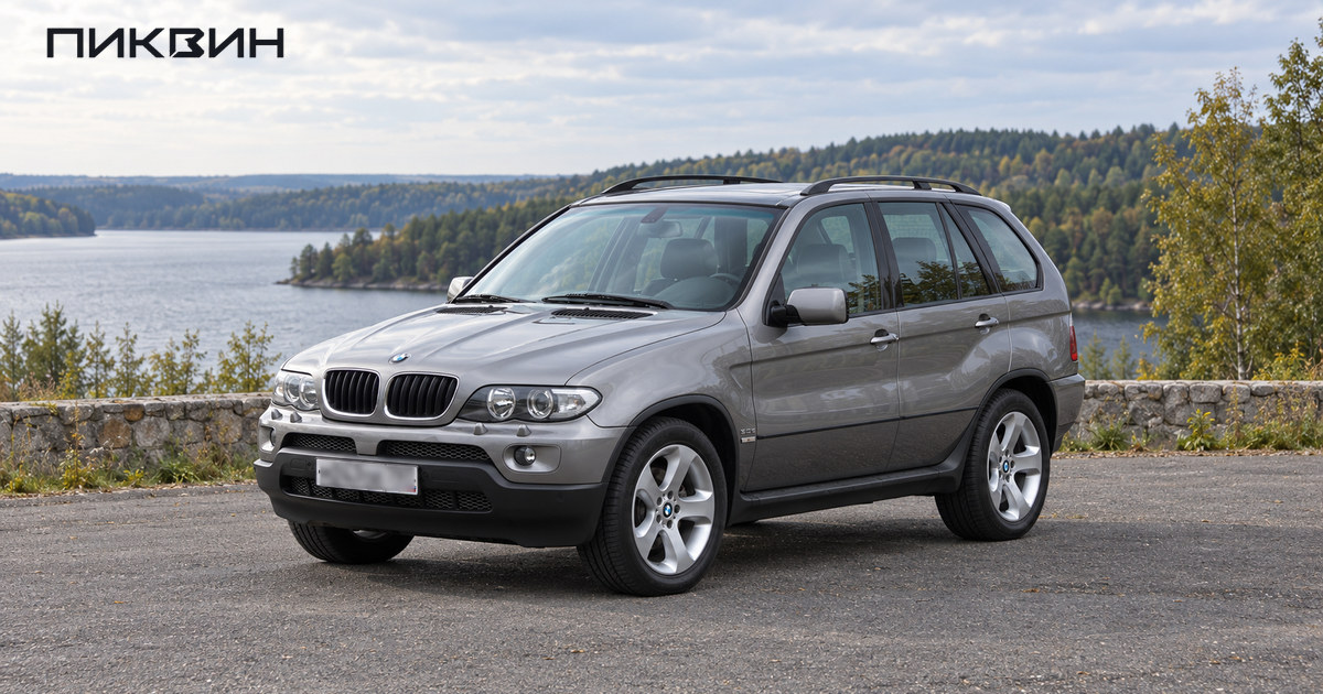 Серебристый BMW X5 первого поколения E53 стоит на свободной площадке у загородной дороги.