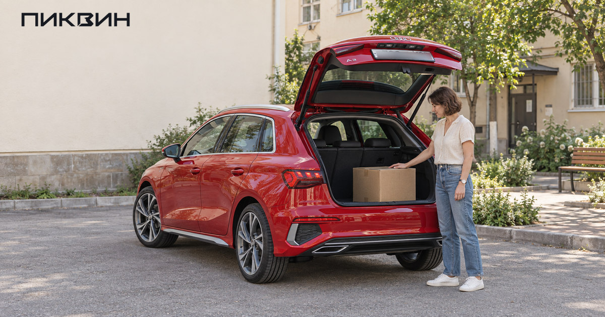 Покупательница проверяет размещение коробки в багажнике красного Audi A3 Sportback.