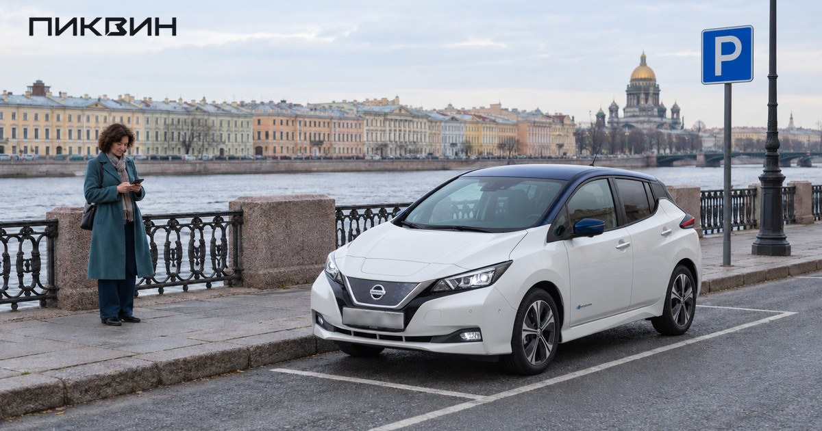 Белый Nissan Leaf припаркован у набережной, владелица проверяет телефон на тротуаре